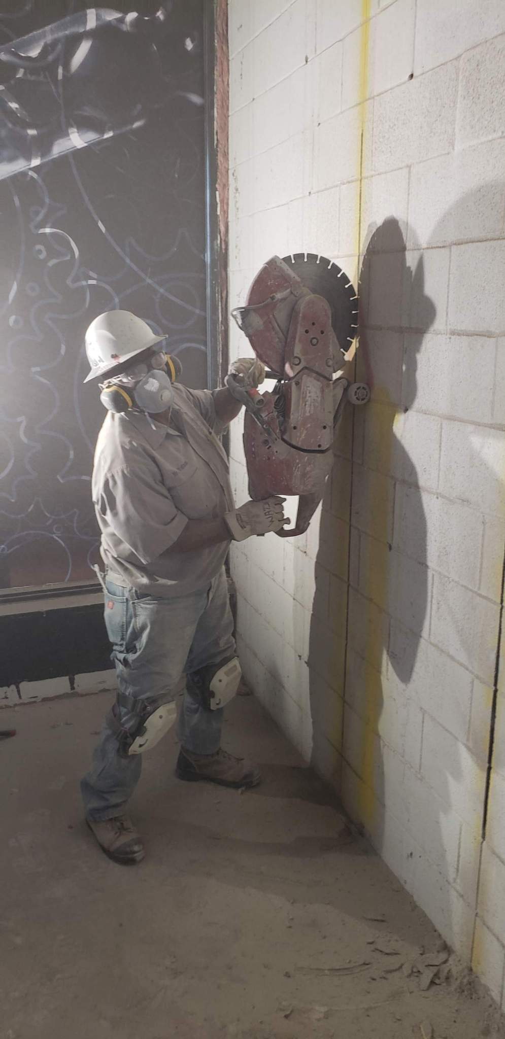 Worker safely cutting a concrete block wall